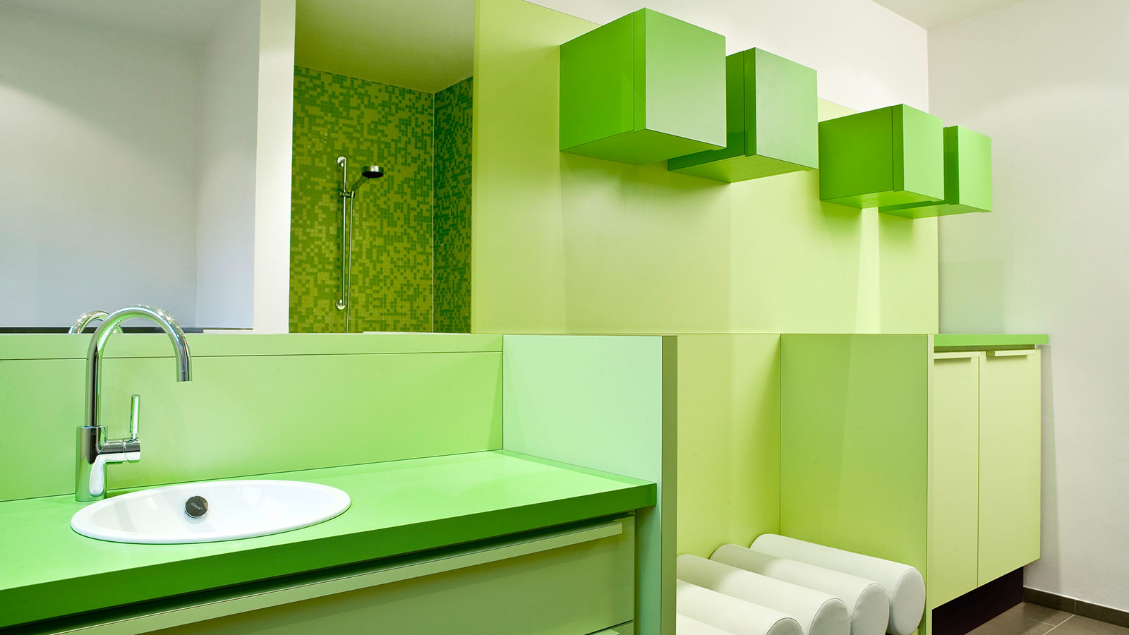 Ein Kinderbad in erfrischendem Grün und mehrfarbiges grünes Glasmosaik in der Dusche